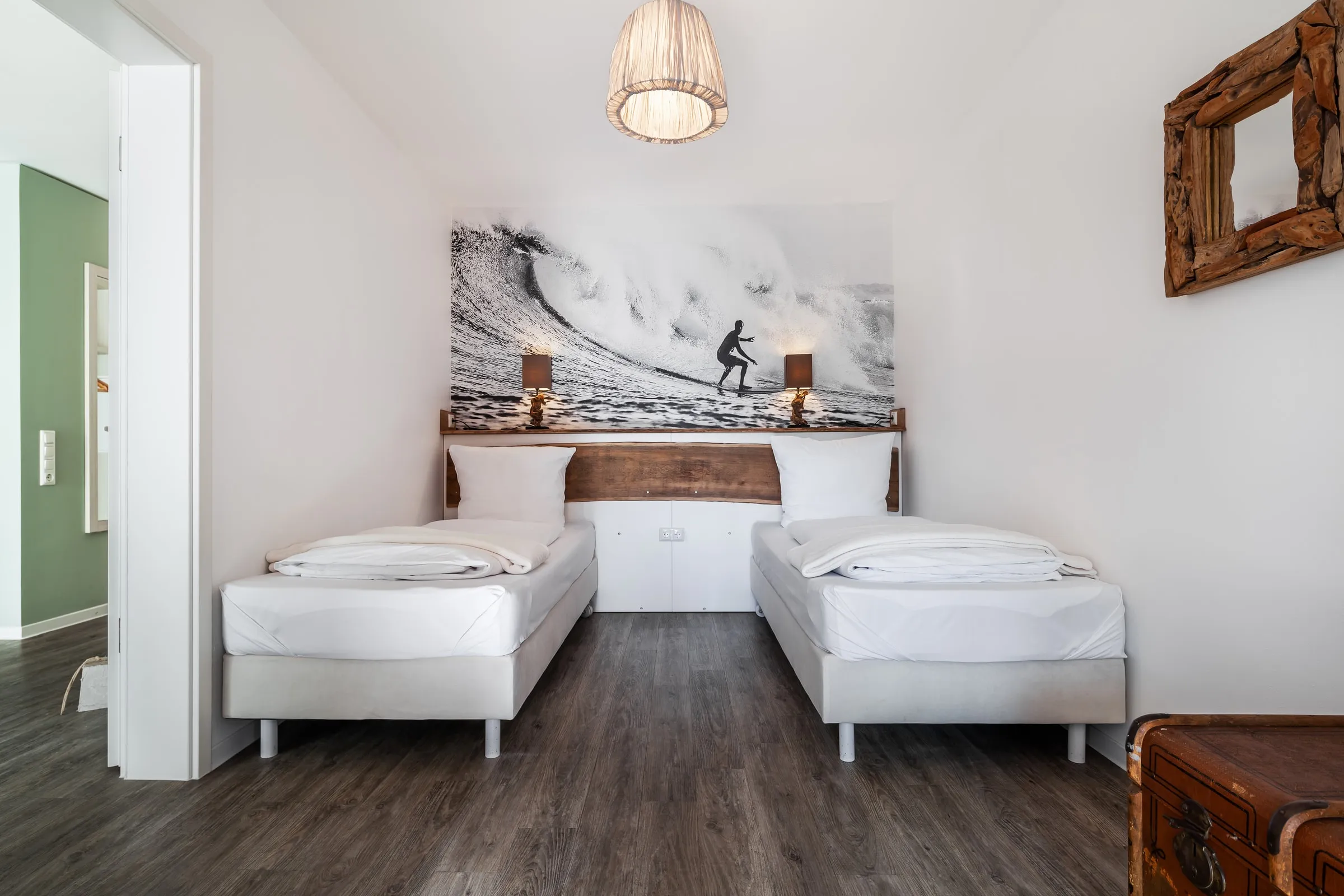 Zweites Schlafzimmer mit zwei Einzelbetten unter einem Schwarzweißbild eines Surfers